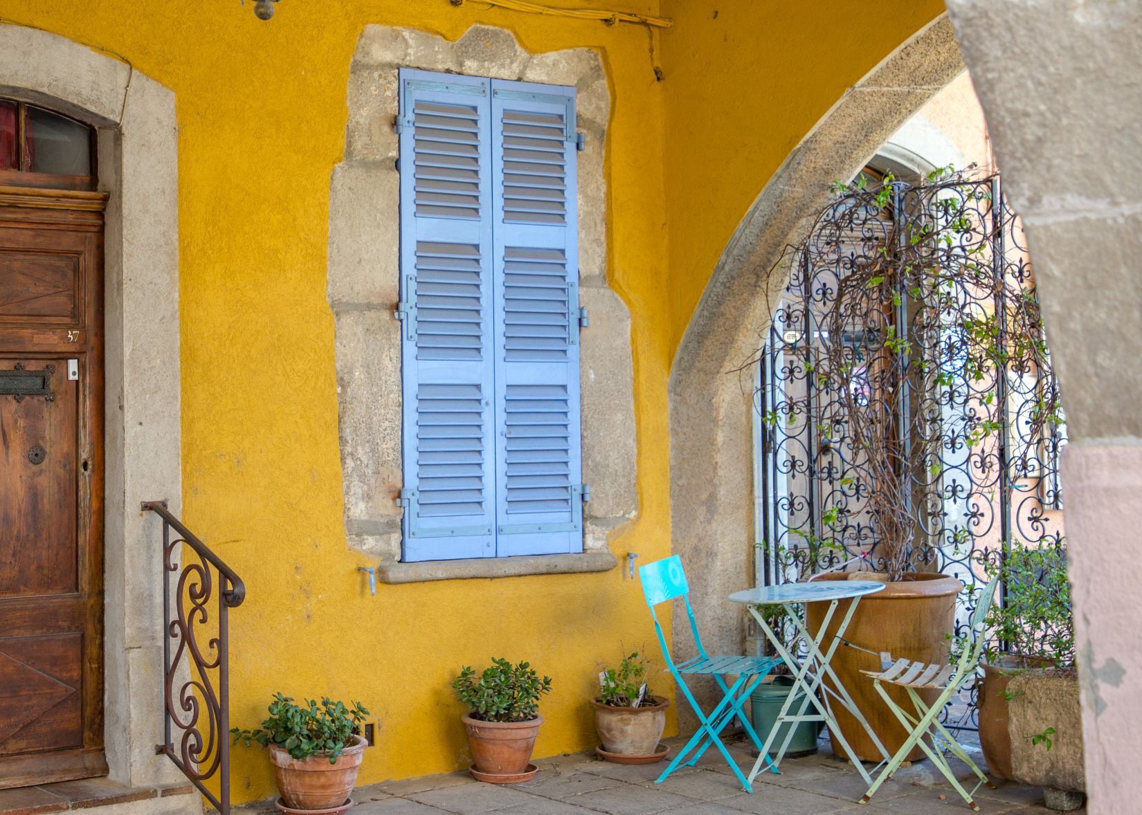 portique de Roquebrune, maison arcade jaune avec table et chaise en fer