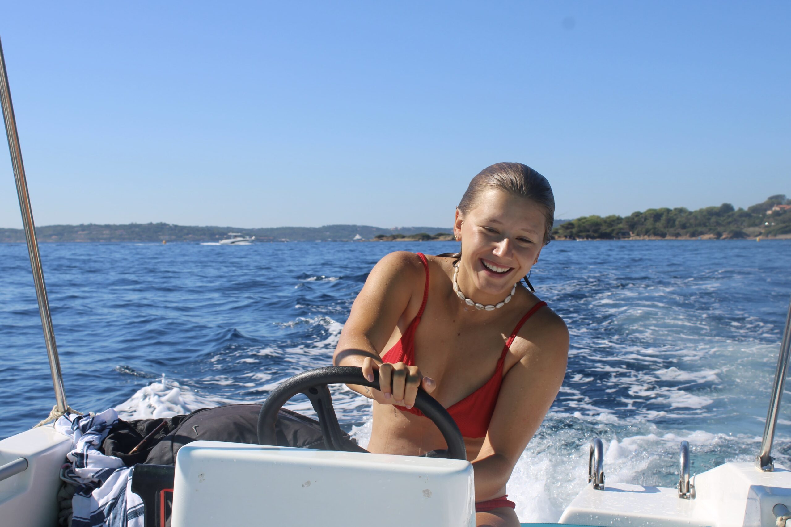 Jeune femme pilotant un bateau sans permis au large des Issambres sur la Côte d'Azur.