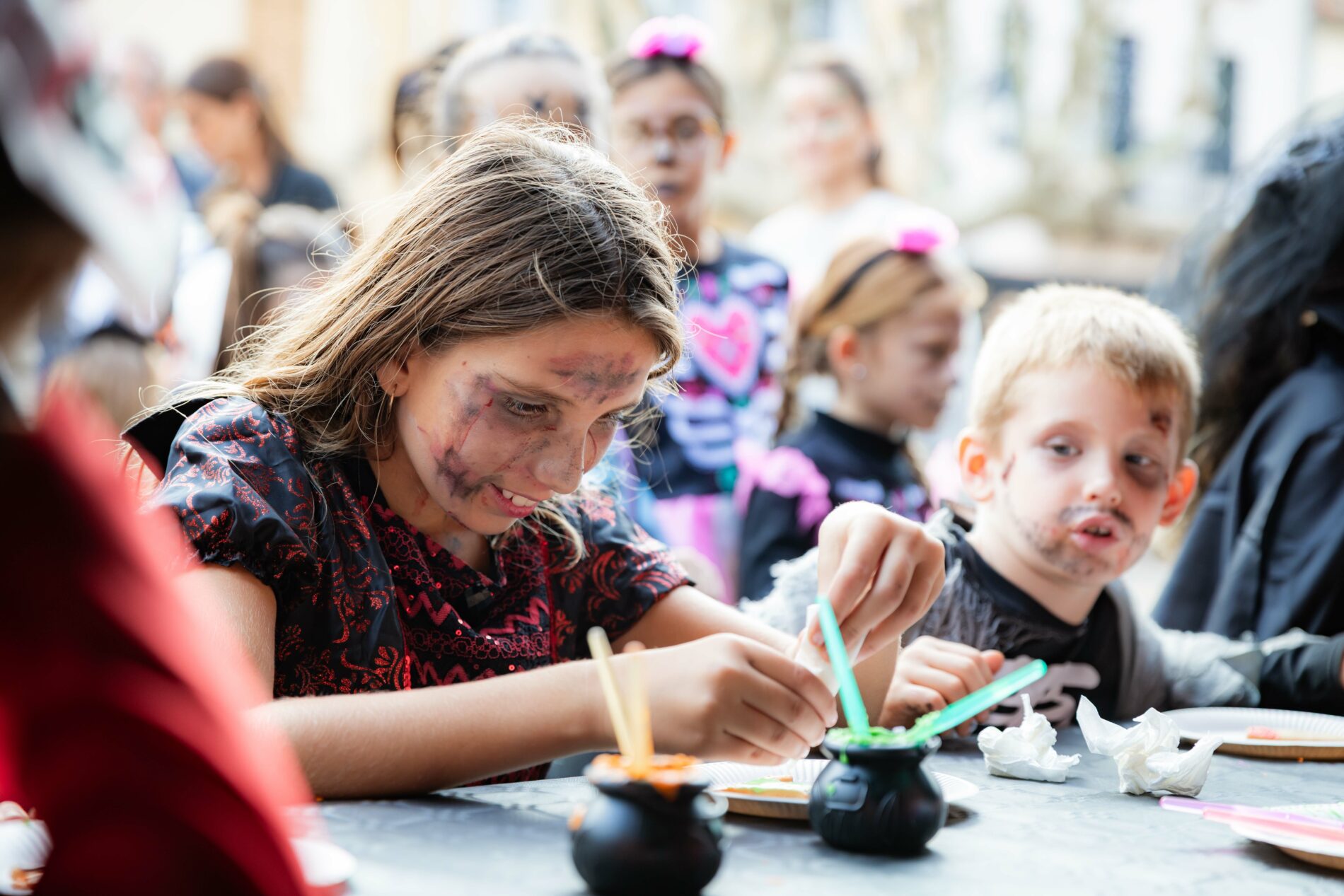 Enfants déguisés participant à un atelier créatif d'Halloween à Roquebrune-sur-Argens, avec maquillage et petits chaudrons.